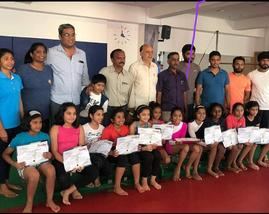 Students holding certificates with parents and coaches