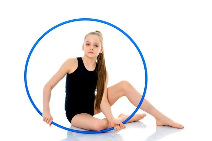 A teenage gymnast sitting inside a hoop