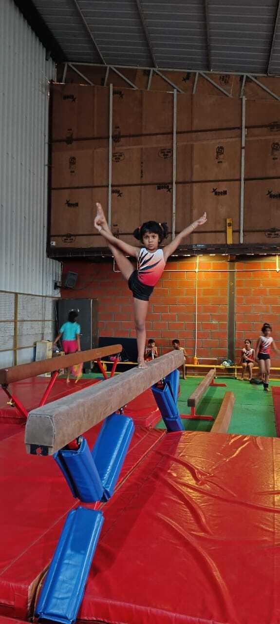 A young gymnast balancing on the beam with one leg raised high