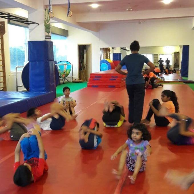 Children stretching on the red floor mats during a class at Aerial Zone