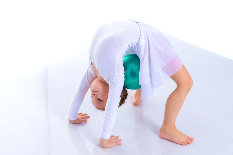 A young child doing a bridge on a white mat